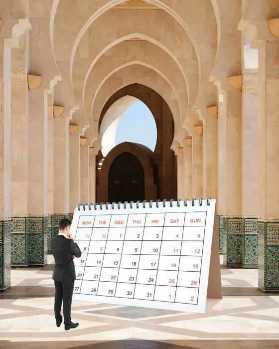 A man studying a large calendar in a tiled Moroccan courtyard with tall arches