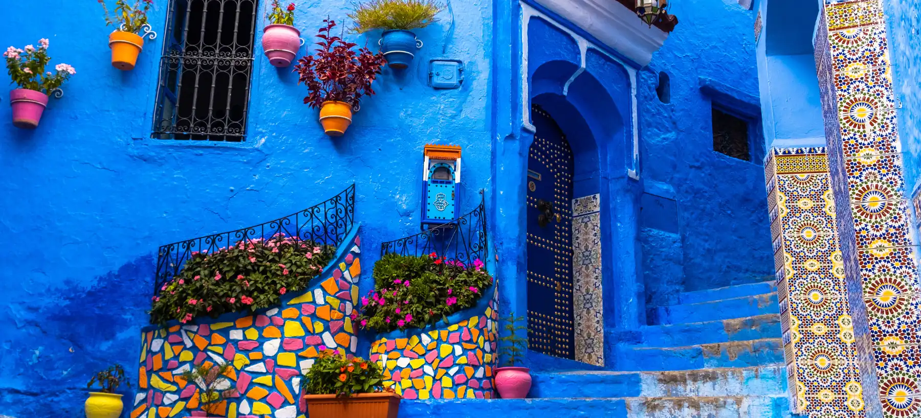 A blue-painted lane in Chefchaouen with tiled steps and flower pots