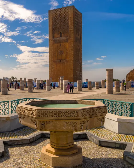 The Hassan Tower and rows of stone columns in Rabat, behind a carved stone fountain