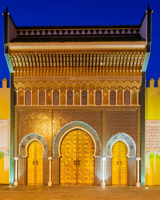The brass doors and tiled gateway of the Royal Palace in Fez, lit at dusk