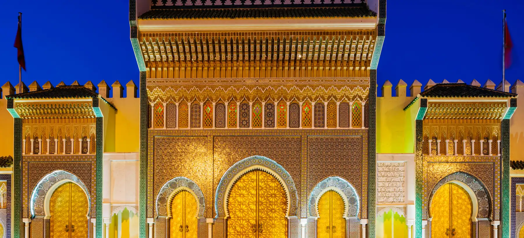 The brass doors and tiled gateway of the Royal Palace in Fez, lit at dusk