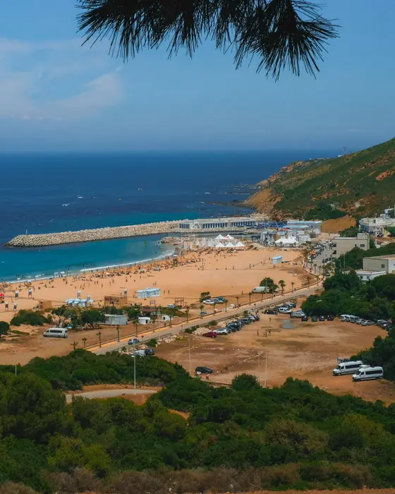 A wide sandy bay and harbour near Tangier seen from green hills