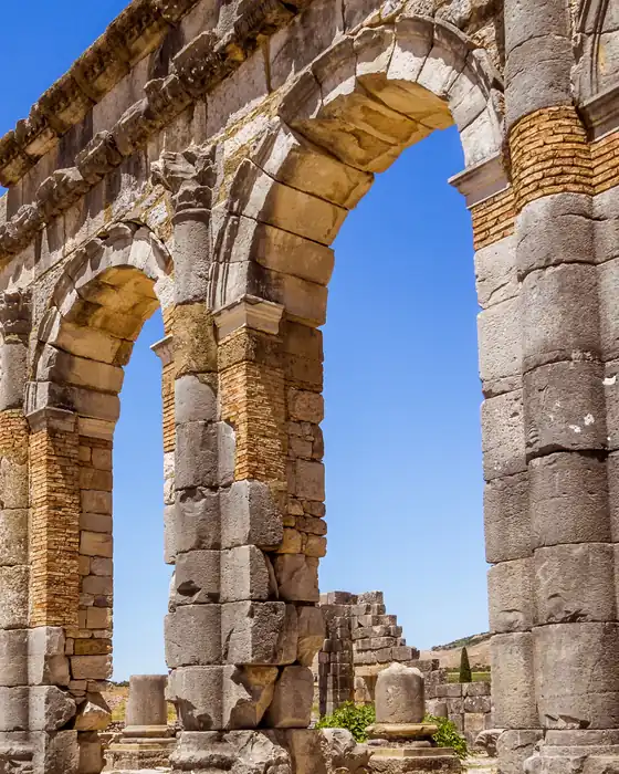 Roman arches and stone columns at Volubilis under a blue sky