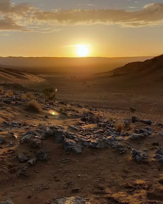 The sun setting over the stony desert near Zagora, between low hills